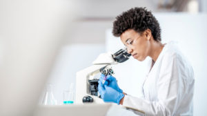 A scientist using a microscope to assist with her work on gene therapy