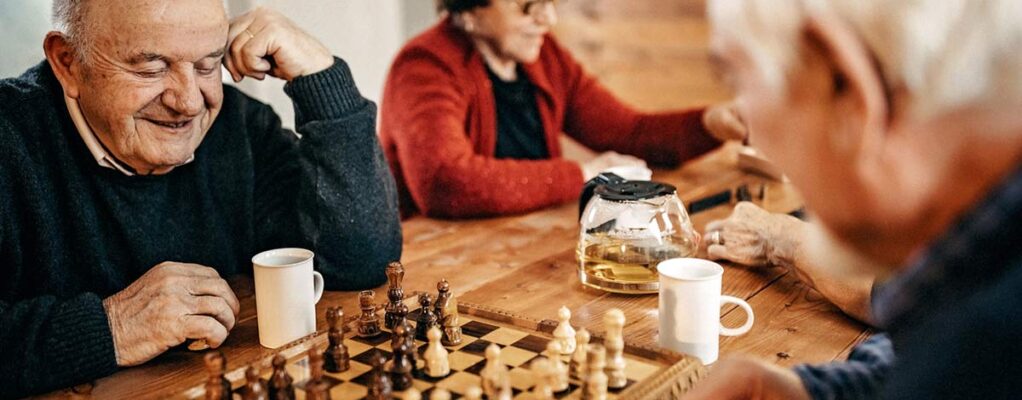 Group of elderly people playing chess and drinking coffee