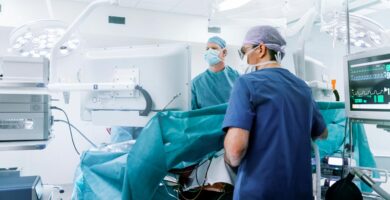 Doctors in blue scrubs work on a patient in an operating room