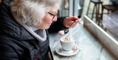 An older woman enjoying a sugary coffee with whipped cream