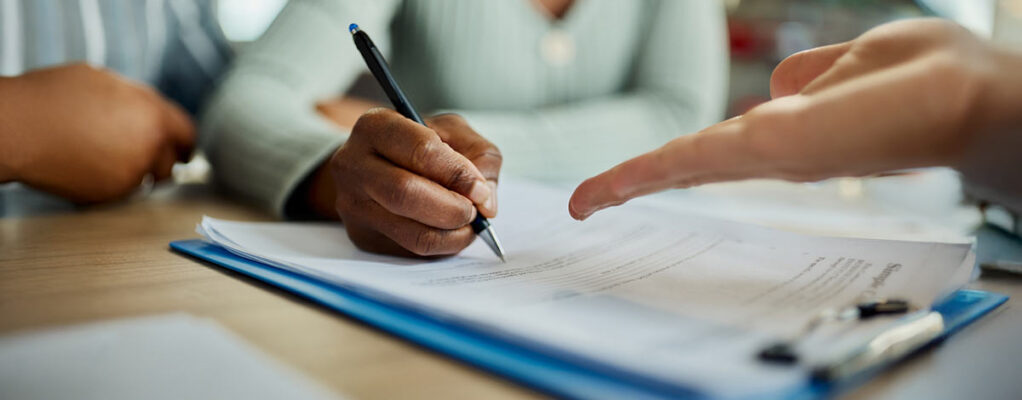 Closeup of people signing documents at a table