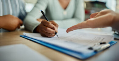 Closeup of people signing documents at a table